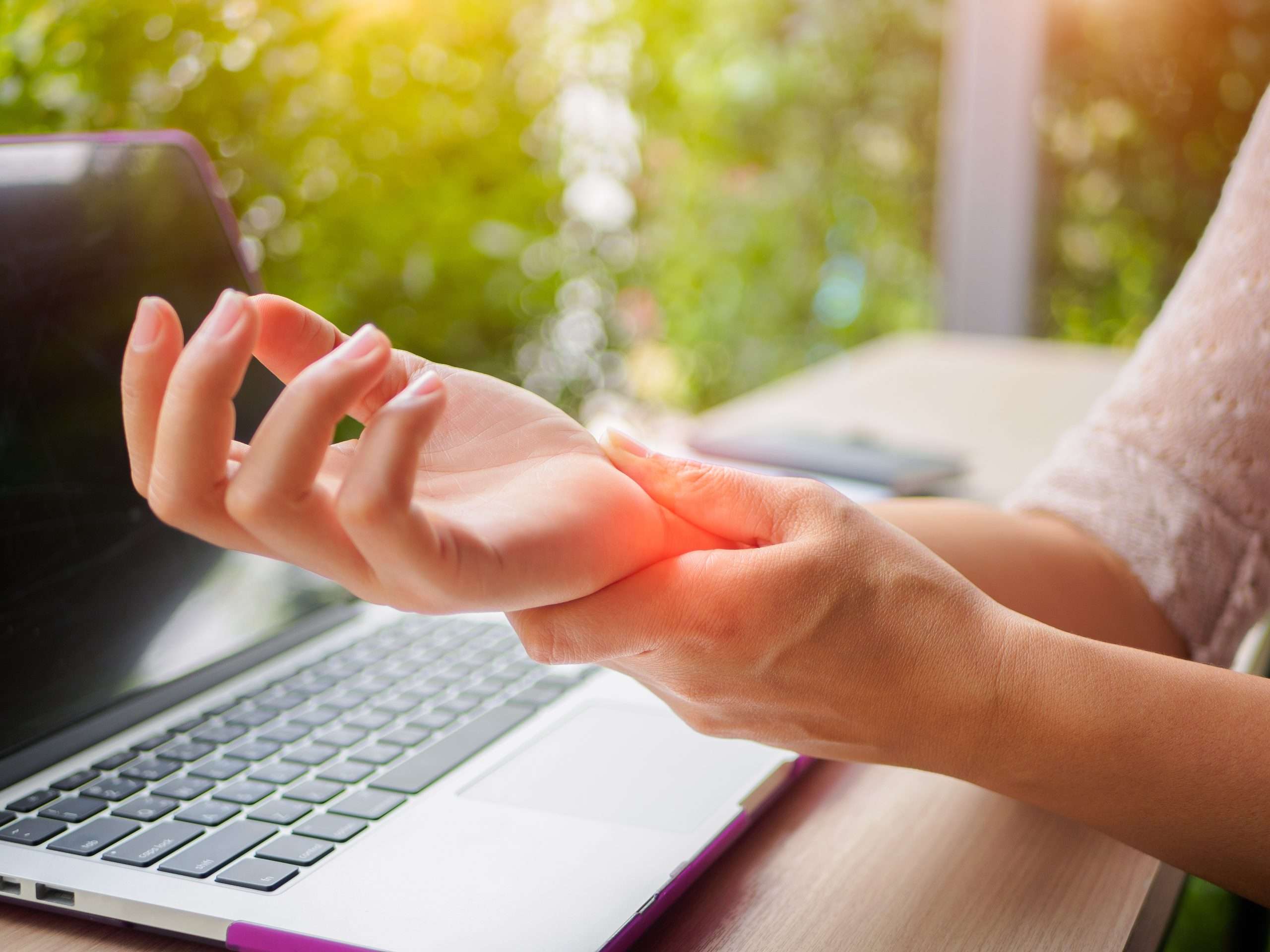 Closeup woman holding her painful hand from using computer. Office syndrome hand pain by occupational disease.