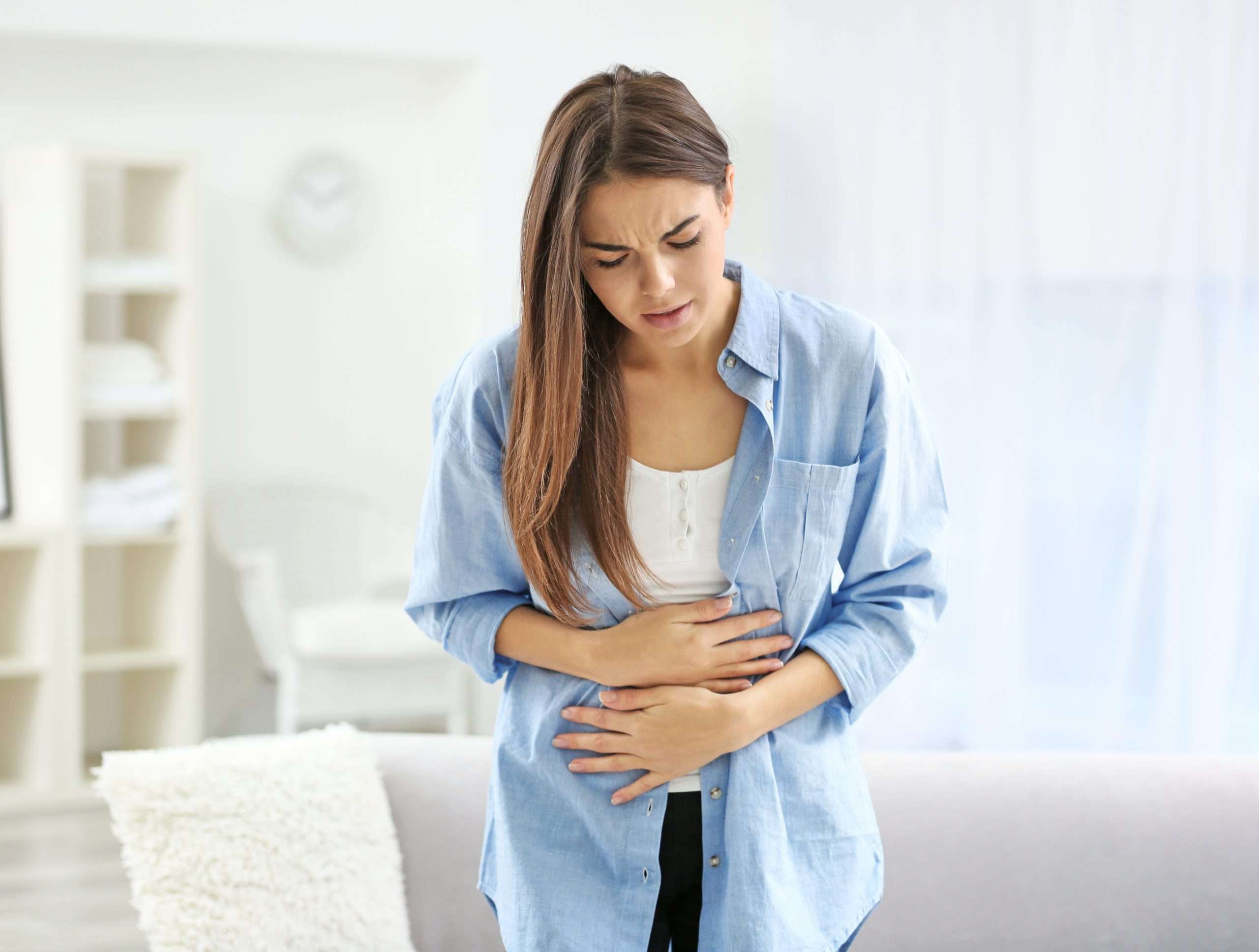 young woman suffering from abdominal pain at home. gynecology co